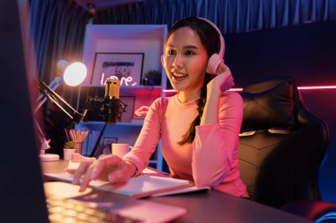 Geceleri podcast 'te olumlu konuşmalar yapan, pembe neon ışıklı modern stüdyoda sunum için dizüstü bilgisayar kullanan, gülümseyen, genç, güzel Asyalı bir etkileyiciydi. Taktik.