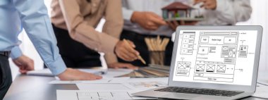 İç mimar tasarımcı grubu, daha kesin tasarım için planlar ve dizüstü bilgisayar ekran mimari yazılımı üzerinde birlikte tartışıyorlar. Modern ev tasarımı ve yenileme. İçgörü