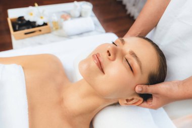 Kafkasyalı kadın stres önleyici kafa masajından ve lüks tatil beldesi ya da otel spa salonundaki modern ışık ortamında yüz güzelliği eğlencelerini şımartmaktan hoşlanıyor. Sessiz.