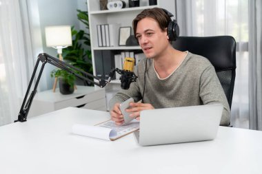 Sunucu kanalı, gülümseyen akıllı yayıncı kaydı, senaryosu ve akıllı telefonuyla sosyal medyada sohbet programı, kulaklık takarak modern ev stüdyosundaki video flamalarını kaydediyor. Bireysel.