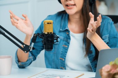 Sosyal medyada kulaklıkla canlı yayın yapan Asyalı sunucu modern stüdyoda yaşam koçluğu veya pazarlama dinleyicilerini selamlıyor. Taktik.