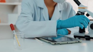 Laboratuvar kimya araştırmacısı mikroskop kullanarak yeni ilaç ya da tedavi geliştirir. Laboratuvar mikrobiyoloji ekipmanları ile bilimsel uzmanlık ile sağlık hizmetlerinin teknolojik gelişimi. Ağır çekim. Katı.