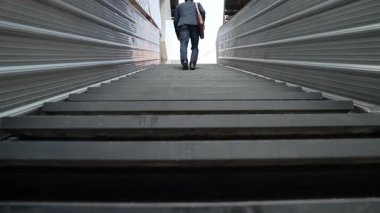 Merdivenlerden çıkan başarılı iş adamının bacağına yakın plan. Müdürün iş yerini değiştirmesi, yeni bir şey keşfetmesi, gelişmesi, terfi etmesi ya da gün ışığına çıkması. Yükseliyor. Bacağa odaklan. Sevinçli..