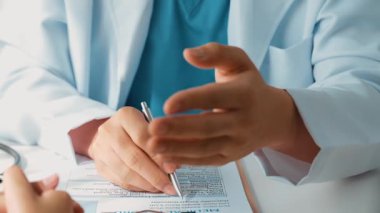 Hastanedeki doktor masasında oturup hasta test sonuçlarını teşhis eden, hastalıklar ve hastalıklar için tedavi planı geliştiren evrak işleriyle uğraşıyor. Sağlık personeli ve sağlık hizmetleri. Ağır çekim. Katı.