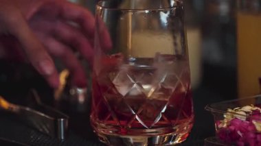 Yakın plan el yapımı barmen karışık alkollü likör şurubu karıştırıp buzla karıştırıyor. Barda eski moda kokteyl tatma kokteyli hazırlıyor ve gece hayatı karışımı sergiliyor. Vinosity.