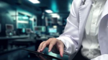 Profesyonel doktorun DNA örneği hologramını alıp hologramı laboratuvarda yüzerken tablete koymasına yakın durun. Tıbbi verileri uygulayan ve genetik bozuklukları analiz eden bir tıp çalışanı. İyileştirici.