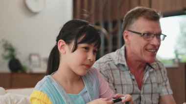 Büyükbaba ve torun birlikte konsol oyunu, eğlence medyası oynuyorlar. Eski kullanım teknolojisi yeni nesil ile iletişim kurar. Nesiller arası uçurum aile bağını güçlendirir. Uyumsuzluk.