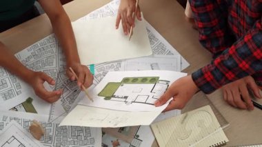 Mimari döküman, ölçüm araçları ve ahşap blokların modern ofiste etrafa saçıldığı masa üzerine planlar yapma konusunda akıllı mimar ve güvenlik mühendisi tartışması. - Yakın çekim. Tanımlama.