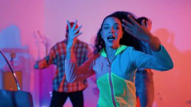 Çekici break dansçı, stüdyo arkasında neon ışıkla dans ederken kameraya bakıyor. Profesyonel sanatçı, serbest stile ve hip hop müziğine geçiş yaparken gündelik giysiler giyiyor. Mutluluk.