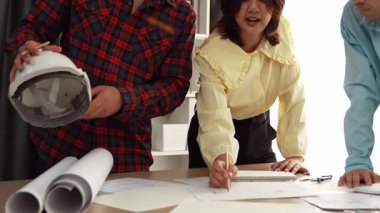 Mimari döküman, ölçüm araçları ve ahşap blokların modern ofiste etrafa saçıldığı masa üzerine planlar yapma konusunda akıllı mimar ve güvenlik mühendisi tartışması. - Yakın çekim. Tanımlama.