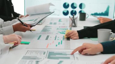 Modern ofis ortamında çeşitli profesyoneller arasında mali raporlar ve etkileşimli veri analizlerinin yer aldığı, işbirliği ve yaratıcılığın teşvik edildiği dinamik bir iş toplantısı. SACTR