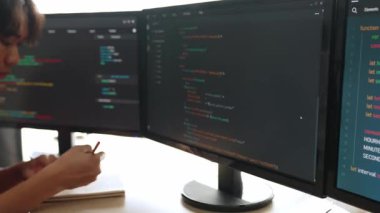 Yavaş çekim arkası yazılım geliştirici mühendisi bilgisayar programlama için birlikte çalışarak hata ayıklama kodunu çözüyor, ofiste monitörde karmaşık algoritmaları çözüyor. Filizlenen