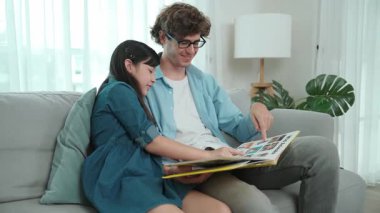 Beyaz bir baba ve tatlı bir kız kanepede otururken masal kitabı okuyorlar. Mutlu bir baba, sevimli bir Amerikan çocuğuna, birlikte zaman geçirirken hayal gücünün gelişmesi için hikaye anlatıyor. Pedagoji.