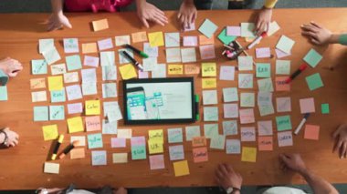 Ux Ui tasarımı kullanılarak dijital program ve yazıları tartışan ve gösteren geliştirici ekibin hava görüntüsü. İş dünyasına tepeden bakan insanlar telefon ve bilgisayar için kablo prototipi geliştiriyorlar. Sempozyum.