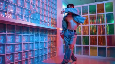 Çekici Asyalı sanatçı parlak neon ışıkta adım atıyor. Kameraya özgüvenle bakarken serbest stil müzikle dans eden yakışıklı break dans. Profesyonel hippi rahatla. Mutluluk.