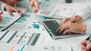 Çeşitli bir iş ekibi modern bir çalışma istasyonunda işbirlikçi veri analizi yapıyor. Eller dizüstü bilgisayarda ve belgelerde gösteriliyor, takım çalışması ve stratejik planlama vurgulanıyor. SACTR