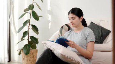 Kanepede oturan bir kadın ders kitabı okuyarak sosyal ve mesleki teknoloji bilgisini artırır ya da akıllı bir anne olmak için çocuk yetiştirir. Hayat boyu öğrenme konsepti. Uyumsuzluk.