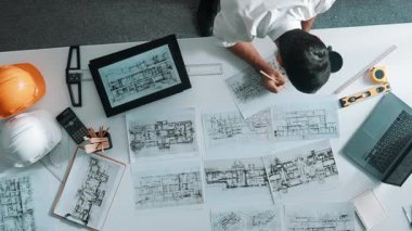 Bina yapısını analiz etmek için dizüstü bilgisayar kullanırken tablete bakan mühendislerin yukarıdan aşağı görüntüsü. Proje planıyla toplantı masasında iç tasarımı kontrol eden mimarın hava görüntüsü. Hizalama.