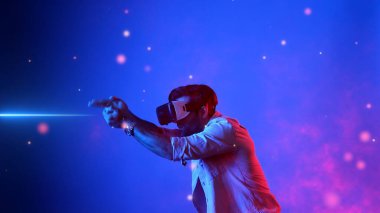 Yetenekli oyuncular silah olarak el ele tutuşup VR gözlük takıp atış oyunu oynayarak metaevrene girebiliyor. Çekici erkek model mavi arka planda dururken hareket ediyor ve oyuncuyu hedef alıyor. Aygıt.