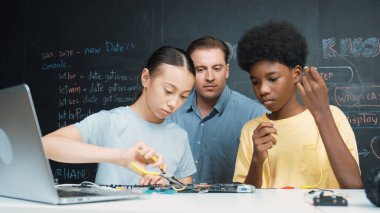 Kafkas öğretmeni elektrikli aletten bahsederken öğrenci de elektronik ekipmanlarla robot modelini tamir ediyor. Çeşitli akademik çocuklar ana kurul yapısını öğreniyor. Öğretim.