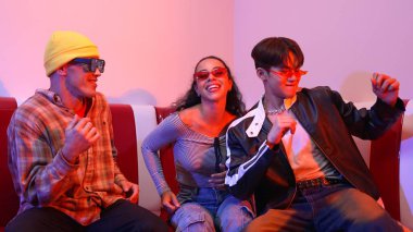 Mutlu kız kameraya bakıyor ve kanepede otururken pop müzik dinliyor. İspanyol kadın serbest stil dans ederken kameraya bakıyor neon ışıkta çeşitli arkadaşlarla dans ediyor. Mutluluk.