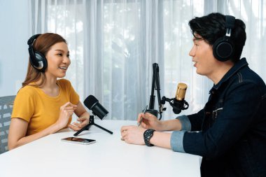 Gülümseyen radyo etkili sunucusu kulaklık takıyor kadın konuşmacı ile röportaj yapıyor sosyal medya internet sitesinden dinleyicilere bilgi paylaşıyor stüdyo kaydında sabah canlı yayın kanalı. İnfobahn.