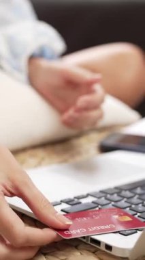 Genç bir kadın internet bankacılığı için kredi kartıyla dizüstü bilgisayar kullanıyor. Evinde online ödeme kapısı ile E ticareti yapıyor. Banka kartıyla modern ve kullanışlı online satın alma. Blithe