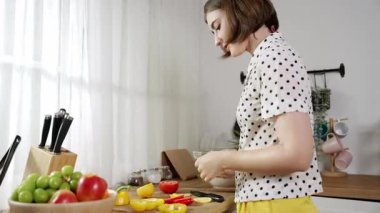 Kafkaseli anne kahvaltıda sebze pişirirken mutlu anne de modern mutfakta salata için taze malzemeler hazırlıyor. Hizmetçi sağlıklı yemek pişiriyor. Dikkat konsepti. Pedagoji.