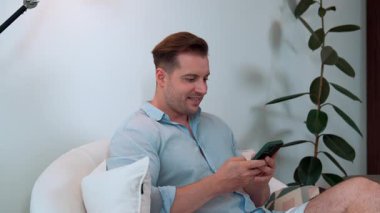 Orta yaşlı bir adam oturma odasındaki koltukta oturur telefon arama verilerini kullanır çocukları iyi bir yetişkin baba ya da eğlence olarak yetiştirir. İşadamı teknolojiyi kolaylık için kullanır. Uyumsuzluk.