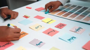 Yaratıcı proje planlaması ve takım beyin fırtınası oturumları için ideal, çeşitli renkli post-it ve renk örneklerinin yer aldığı işbirlikçi bir çalışma alanı. SACTR