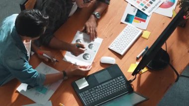 Takım ayakta dikilirken ve yorum yaparken müdürün fikir yazma konusunda üst düzey görüşü. Profesyonel tasarımcı logosu renk paletine bakarken ve renkli kalemle fikri kağıda yazarken. Sempozyum.