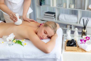 Sıcak bitkisel top spa masaj vücut tedavisi, masör kadın vücuduna nazikçe şifalı bitki torbası bastırıyor. Aromaterapi dinlenme sükuneti ve sükuneti kaplıca salonundaki atmosferi aydınlatıyor. Sessiz.