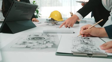 Profesyoneller dinamik bir toplantı yaptılar, modern bir ofiste mimari planları ve mühendislik çizimlerini analiz ettiler, işbirliği ve yenilikçi fikirleri teşvik ettiler. SACTR