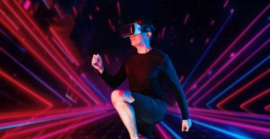 Parlak pembe ve mavi renkli soyut bir arka planda egzersiz yaparken VR kulaklık takan Asyalı bir adam. Çekici erkek model, siyah vücut giysisi giyerken spor yapıyor. Teknoloji. Yaratıcılık.