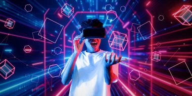 VR gözlük takan zeki bir genç ve geometrik şekil konusunda heyecanlı. Afrikalı oyuncu gündelik kıyafet giyiyor ve artırılmış gerçeklik teknolojisi kullanırken parlak ışık rengiyle çevrili. Yaratıcılık.