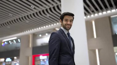 Beyaz arka planda dururken kameraya bakan bir iş adamı. İş elbisesi giyerken kameraya gülümseyen başarılı adamın yakın çekimi. Yönetici, kameraya bak. Hareket eden kamera. Sevinçli..