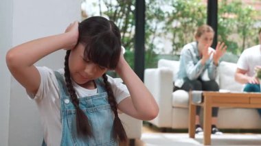 Stresli ve mutsuz genç kız köşeye kıvrılıp kulaklarını kapatarak arka planda ebeveyninin tartışmasını engelliyor. Evde aile içi şiddet ve travmatik çocukluk depresyona dönüşür. Titiz