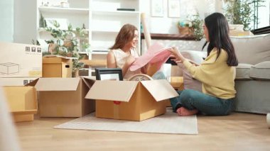 Oturma odasında karton kutuyla otururken konuşan ve oynayan mutlu lezbiyen sevgili. İki kız yeni eve taşınıyor ve birlikte konuşup yardım ediyorlar. Destekleyici kavram. Myrmidon.