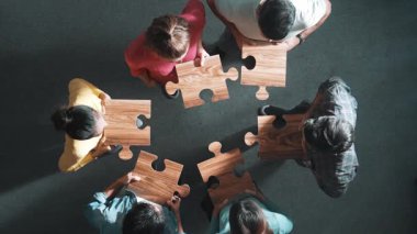 İş adamlarının toplantıda yapboz toplaması. Çeşitli takımların havadan görünüşü yapboz parçalarını bir araya toplar ya da birleştirir ve günlük giysiler giyerek ayakta dururlar. Sempozyum.