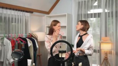 İki kadın nüfuzlu partner sosyal medya veya blog için canlı yayın yapan video klip inceleme derisi çekiyorlar. Kozmetik stüdyosu ışıklandırması olan genç bir kız pazarlama oturumu çevrimiçi yayın yapıyor.