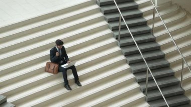 Üst düzey bir iş adamı merdivenlerde otururken başarılı bir projeyi kutluyor. Proje yöneticisi yeni bir pozisyon alıyor, terfi alıyor, arkadaşlarını ararken dizüstü bilgisayar kullanarak satışları artıyor. Sevinçli..