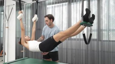 Pilates eğitmeni, Cadillac teçhizatı üzerinde asılı duran bir bacak egzersizinde bir müşteriye rehberlik ediyor. Vücut dengesini sağlamak için Cadillac 'ı geren sağlıklı bir kadın. Alışkanlık.