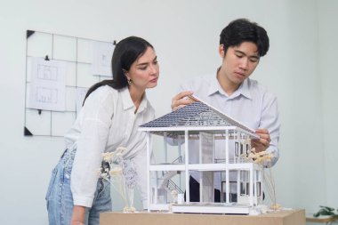 Kooperatif mühendis ekibinin portresi ev modelini ölçmek için cetvel ve mimari ekipmanlar kullanarak birlikte çalışıyor. Yaratıcı iş tasarımı ve takım çalışması konsepti. Tertemiz...