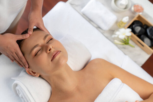 Panorama top view of woman enjoying relaxing anti-stress head massage and pampering facial beauty skin recreation leisure in dayspa modern light ambient at luxury resort or hotel spa salon. Quiescent