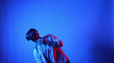 Mutlu dansçı VR gözlüklerini kullanırken enerjik bir hareket yapıyor. Dans ederken ve müzik dinlerken sanal gerçeklik kulaklığı takan sıradan giysili beyaz bir adam. Eğlence konsepti. Aygıt.
