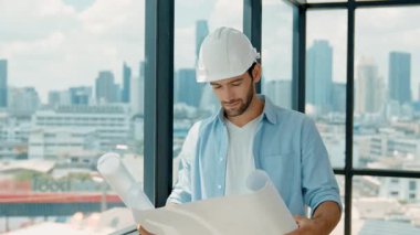 Profesyonel mühendis gökdelen manzarasına bakarken gülümsüyor. Sıradan giyinen yetenekli bir mimar, şehir manzaralı panorama penceresinin yanında dururken plan yapıyor. İzleme