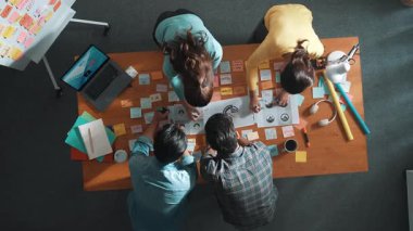 İşletme ekibinin üst görüntüsü toplantı masasına renkli yapışkan notlar ve tasarım ile grafik logo yazarak fikri açıklar. Proje yöneticisi fikri paylaşıyor ve akıllı takıma konsept sanatı anlatıyor. Sempozyum.