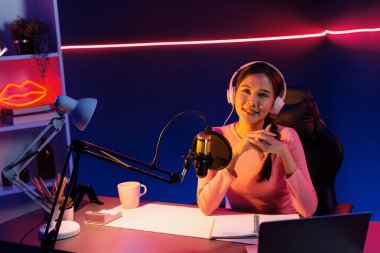 Geceleri podcast 'te olumlu konuşmalar yapan, pembe neon ışıklı modern stüdyoda sunum için dizüstü bilgisayar kullanan, gülümseyen, genç, güzel Asyalı bir etkileyiciydi. Taktik.