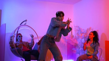 Çok kültürlü bir arkadaş kürsüde otururken Asyalı yetenekli bir dansçı modern müziğe geçiyor. Profesyonel dansçı, hipster takımı tezahürat yaparken ve desteklerken enerjik adımlar atıyor. Mutluluk.