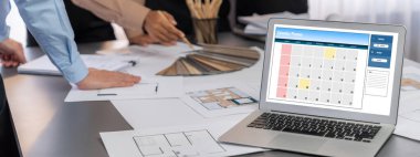 İç mimar tasarımcı grubu, daha kesin tasarım için planlar ve dizüstü bilgisayar ekran mimari yazılımı üzerinde birlikte tartışıyorlar. Modern ev tasarımı ve yenileme. İçgörü